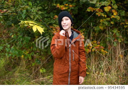 The boy is standing on the street and pulls a hat on his face 95434595