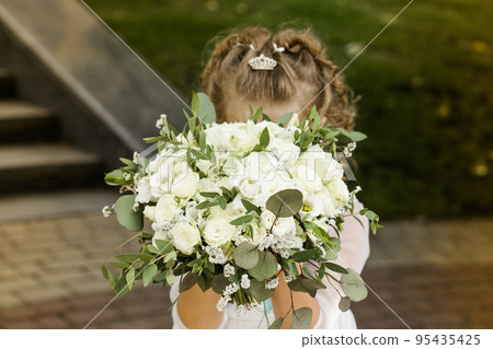 Little girl holding a bridal bouquet in her hands Little girl holding a bridal bouquet in her hands 95435425