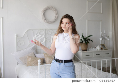 Thoughtful emotional European girl in a white top is talking on the phone. Thoughtful emotional European girl in a white top is talking on the phone. 95435852