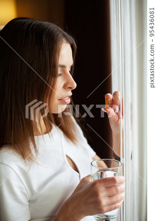 Woman taking vitamin pill with glass of fresh water indoors. Woman taking vitamin pill with glass of fresh water indoors. 95436081