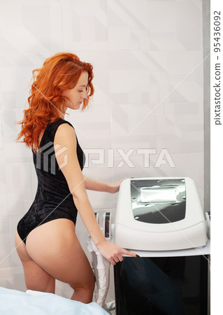 Red-haired woman in a medicine salon, anti-cellulite procedure. Red-haired woman in a medicine salon, anti-cellulite procedure. 95436092
