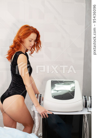 Red-haired woman in a medicine salon, anti-cellulite procedure. Red-haired woman in a medicine salon, anti-cellulite procedure. 95436096