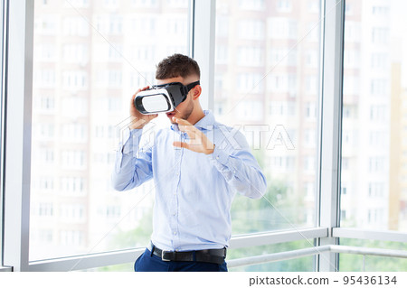 Man in virtual reality glasses interacts with app simulated interface. Man in virtual reality glasses interacts with app simulated interface. 95436134