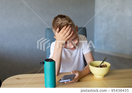 An emotional boy in a white T-shirt connects the speaker to the phone and laughs. An emotional boy in a white T-shirt connects the speaker to the phone and laughs. 95436435