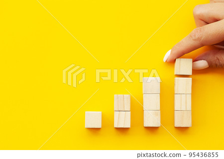 Close up Woman hand arranging wood block stacking as step stair. Close up Woman hand arranging wood block stacking as step stair. 95436855