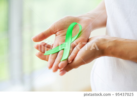 Young woman holding awareness green ribbon as a symbol to awareness Lymphoma cancer 95437025