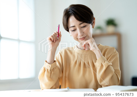 A middle-aged woman who worries while studying in the living room 95437673