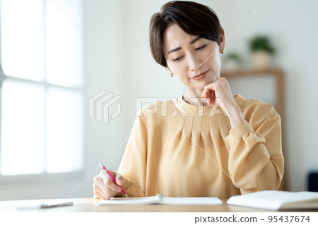 A middle-aged woman who worries while studying in the living room A middle-aged woman who worries while studying in the living room 95437674