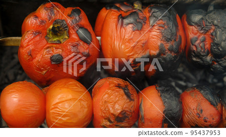 Close-up of bell peppers and tomatoes grilled over charcoal. Top view. Tasty and healthy vegetables cooked on the fire. Close-up of bell peppers and tomatoes grilled over charcoal. Top view. Tasty and healthy vegetables cooked on the fire. 95437953