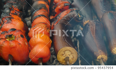Close-up of vegetables on skewers roasting on a charcoal grill. Peppers, tomatoes and eggplants are prepared for a traditional Caucasian dish. 95437954