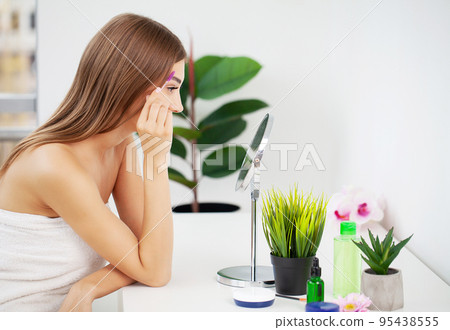 Young beautiful woman making make-up near mirror Young beautiful woman making make-up near mirror 95438555