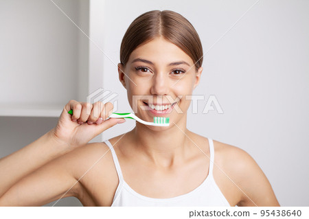 Beautiful young woman brush her teeth in the bathroom 95438640