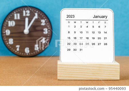 The January 2023 Monthly calendar for 2023 year with clock on wooden table. 95440093