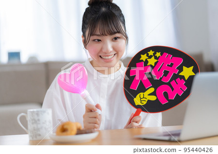 Oshikatsu 一邊看直播視頻一邊揮舞扇子為 Oshi 加油的年輕女子 95440426