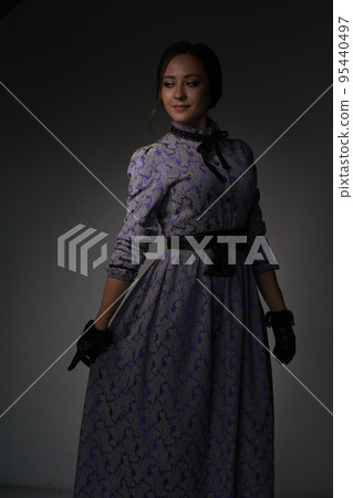 The girl is standing in a blue dress in the style of the 1900s, in a retro dress, on a gray background. Historical fashion of the 19th century. High quality photo The girl is standing in a blue dress in the style of the 1900s, in a retro dress, on a gray background. Historical fashion of the 19th century. High quality photo 95440497
