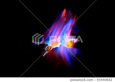 Dance in motion. Studio shot of flying, jumping dancer or gymnast performing tricks in the air over black background with mixed neon glowing rays 95440682