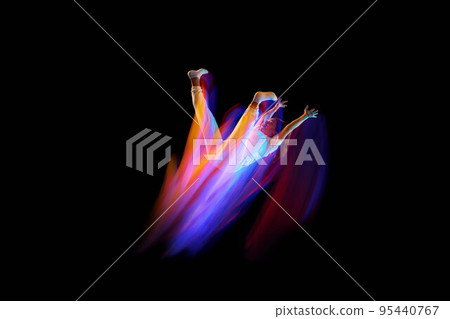 Creative dynamic portrait of athlete, dancer in white sports clothes jumping, flying over dark background in mixed neon light, glow. Art, aspiration, music, fashion 95440767