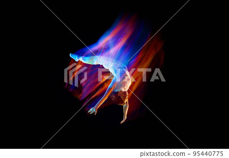 Creative dynamic portrait of athlete, dancer in white sports clothes jumping, flying over dark background in mixed neon light, glow. Art, aspiration, music, fashion 95440775