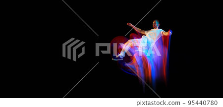 In miracle flight. Young sportive dancer in white clothes levitating, moving over dark background in mixed neon light. Creative art, aspiration, music, fashion, dance 95440780