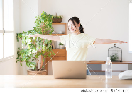 Woman doing online gymnastics indoors Woman doing online gymnastics indoors 95441524