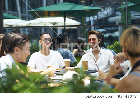 group of young asian adults gathering in outdoor coffee shop 95443078