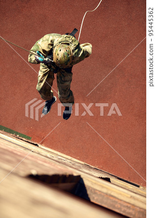 Special forces fighter descends from a skyscraper to storm the apartment. Police, counter terrorism concept. Mixed media Special forces fighter descends from a skyscraper to storm the apartment. Police, counter terrorism concept. Mixed media 95445362