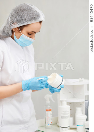 Beautician holding white plastic jar with cream 95445470