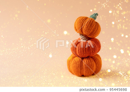 Knitted orange pumpkins on an orange background with festive lights, autumn composition, front view. Halloween concept. Knitted orange pumpkins on an orange background with festive lights, autumn composition, front view. Halloween concept. 95445698