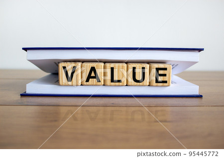 Concept word 'value' on wooden cubes between pages of a book on a beautiful wooden table. White background. Business concept. Concept word 'value' on wooden cubes between pages of a book on a beautiful wooden table. White background. Business concept. 95445772