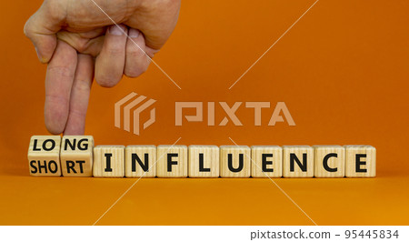 Short or long influence symbol. Businessman turns cubes and changes words 'short influence' to 'long influence'. Beautiful orange background. Business, short or long influence concept. Copy space. Short or long influence symbol. Businessman turns cubes and changes words 'short influence' to 'long influence'. Beautiful orange background. Business, short or long influence concept. Copy space. 95445834