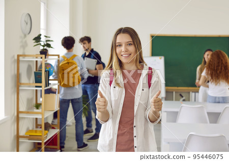 Happy school, college or university student standing in classroom and giving thumbs up 95446075