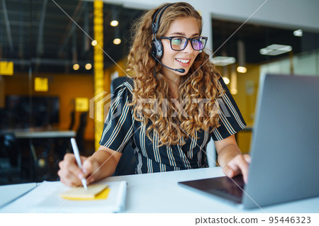 Meeting online. Young woman wearing headphones using laptop watching webinar or doing video chat. Meeting online. Young woman wearing headphones using laptop watching webinar or doing video chat. 95446323