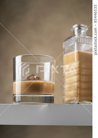Irish cream liqueur alcohol drink in glass with ice cubes. Part drink 95446535