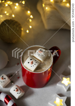 Hot chocolate mug with snowman marshmallows with funny face. Seasonal, winter or Christmas comfort coffee drink. 95446540