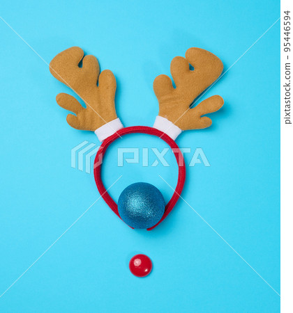 Christmas deer costume with antlers on the head on a blue background, top view. Christmas deer costume with antlers on the head on a blue background, top view. 95446594