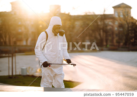 A man wearing special protective disinfection suit sprays sterilizer in the public place. Covid -19. A man wearing special protective disinfection suit sprays sterilizer in the public place. Covid -19. 95447059