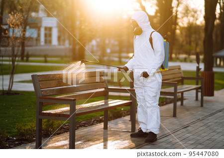 A man wearing special protective disinfection suit sprays sterilizer in the public place. Covid -19. A man wearing special protective disinfection suit sprays sterilizer in the public place. Covid -19. 95447080