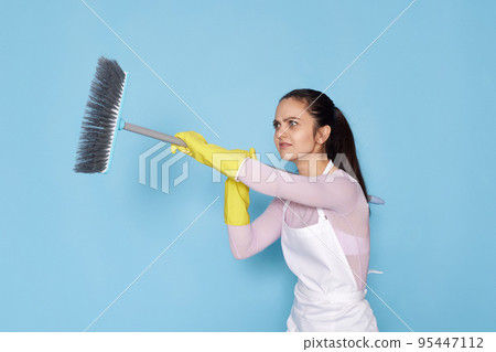 woman in gloves and cleaner apron holding broom 95447112