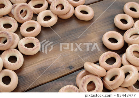 A lot of fresh yellow bagels lie on the surface of the old dark wood. A popular kind of flour products. One of the traditional Russian treats for tea A lot of fresh yellow bagels lie on the surface of the old dark wood. A popular kind of flour products. One of the traditional Russian treats for tea 95448477