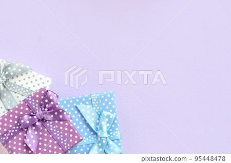 Pile of a small colored gift boxes with ribbons lies on a violet background. Minimalism flat lay top view Pile of a small colored gift boxes with ribbons lies on a violet background. Minimalism flat lay top view 95448478