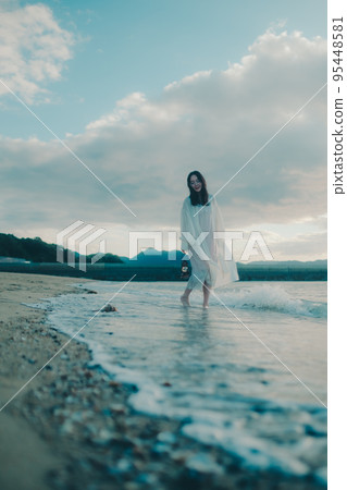 Photo of a woman standing by the beach 95448581