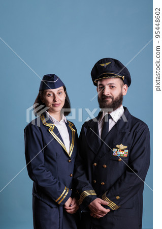 Portrait of airplane aviator and flight attendant wearing flight uniform, looking at camera, medium shot. Professional aviation crew, plane captain and air hostess smiling Portrait of airplane aviator and flight attendant wearing flight uniform, looking at camera, medium shot. Professional aviation crew, plane captain and air hostess smiling 95448602