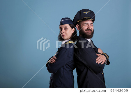 Airplane pilot and flight attendant in professional uniform standing back to back portrait, studio medium shot. Airplane crew, plane captain and air hostess, airline team side view Airplane pilot and flight attendant in professional uniform standing back to back portrait, studio medium shot. Airplane crew, plane captain and air hostess, airline team side view 95448609