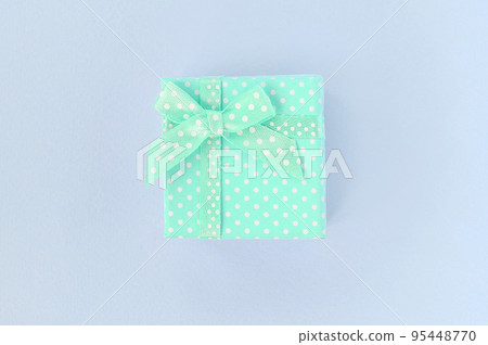 Small blue gift box with ribbon lies on a violet background Small blue gift box with ribbon lies on a violet background 95448770