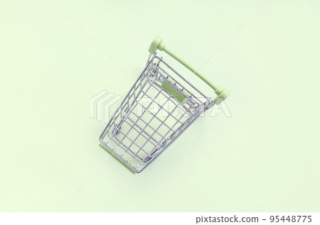 Small shopping cart lies on a lime background. Minimalism flat lay Small shopping cart lies on a lime background. Minimalism flat lay 95448775