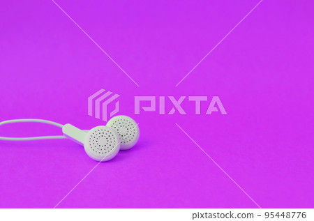 White modern earphones lies on a bright purple background. White modern earphones lies on a bright purple background. 95448776
