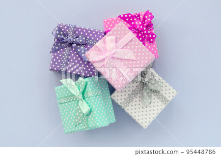 Pile of a small colored gift boxes with ribbons lies on a violet background Pile of a small colored gift boxes with ribbons lies on a violet background 95448786