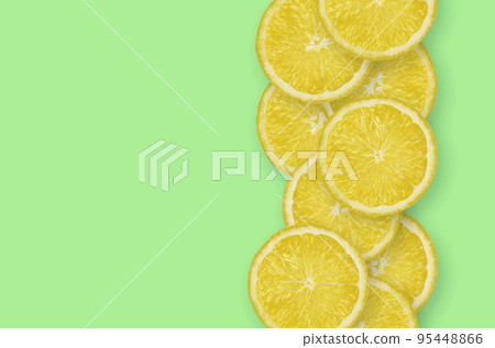 Row of yellow lemon citrus slices on bright lime background Row of yellow lemon citrus slices on bright lime background 95448866
