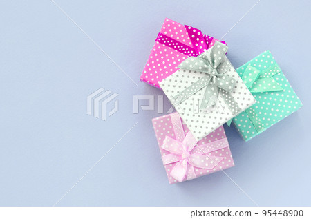 Pile of a small colored gift boxes with ribbons lies on a violet background Pile of a small colored gift boxes with ribbons lies on a violet background 95448900