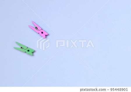 Two colored wooden pegs lie on texture background of fashion pastel violet color paper 95448901